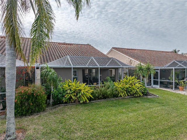 rear view of property featuring glass enclosure and a yard