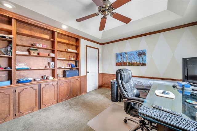 office area featuring ceiling fan, a raised ceiling, built in features, light colored carpet, and ornamental molding