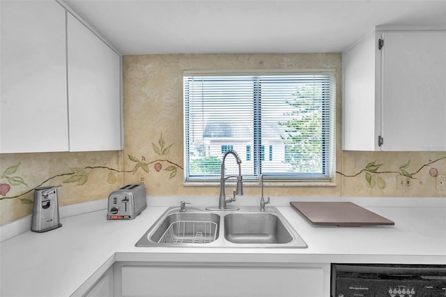 kitchen with dishwashing machine, white cabinetry, and sink