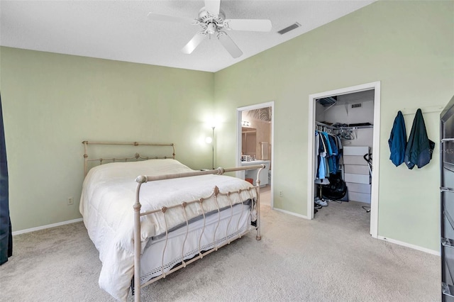 bedroom with a spacious closet, a closet, ceiling fan, and light carpet