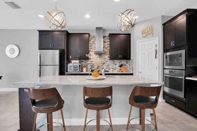 kitchen with a center island with sink, wall chimney exhaust hood, and appliances with stainless steel finishes