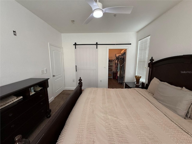 bedroom featuring ceiling fan, a barn door, a walk in closet, and a closet