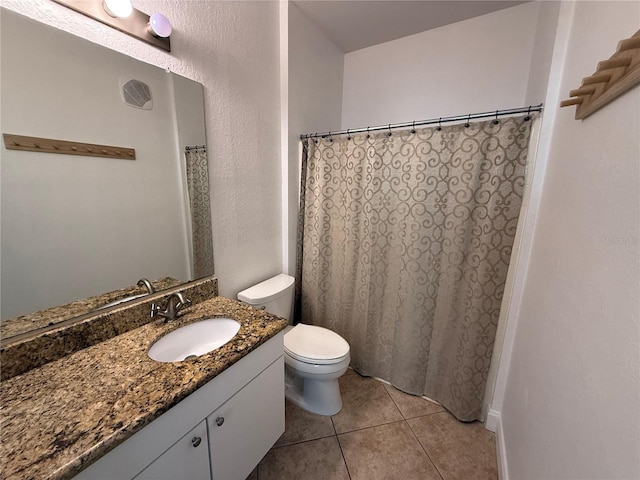 bathroom with toilet, vanity, and tile patterned floors