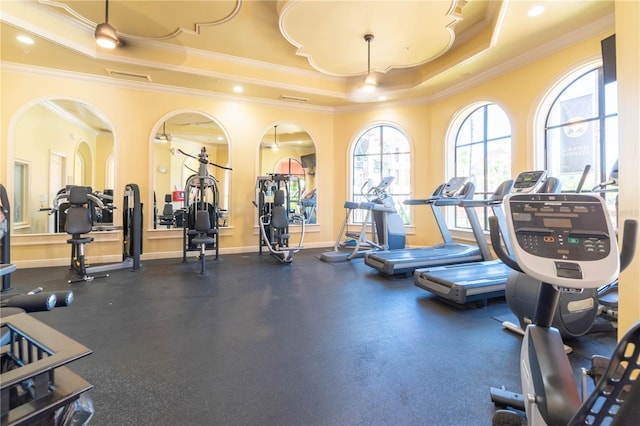 gym with a raised ceiling and ornamental molding