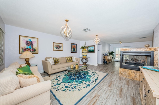 living room with light hardwood / wood-style floors, a tile fireplace, and a chandelier