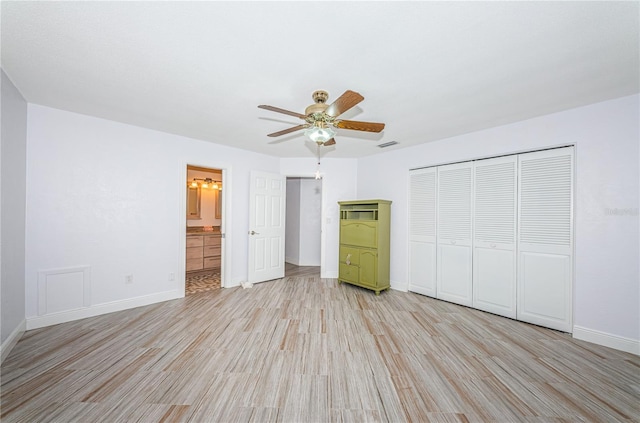 unfurnished bedroom featuring a closet, light hardwood / wood-style floors, ceiling fan, and ensuite bathroom