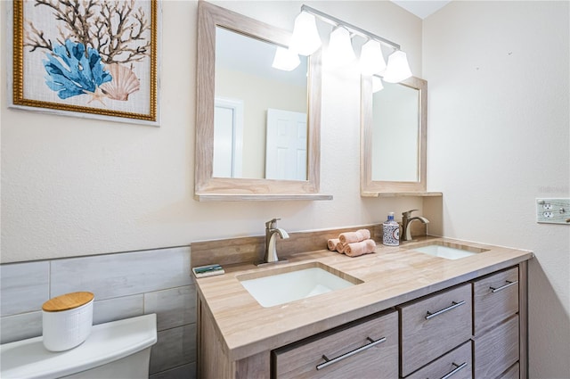 bathroom with vanity, tile walls, and toilet