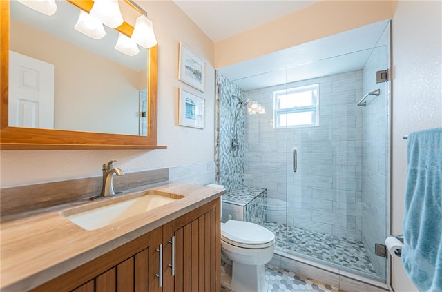 bathroom with tile patterned floors, a shower with door, vanity, and toilet