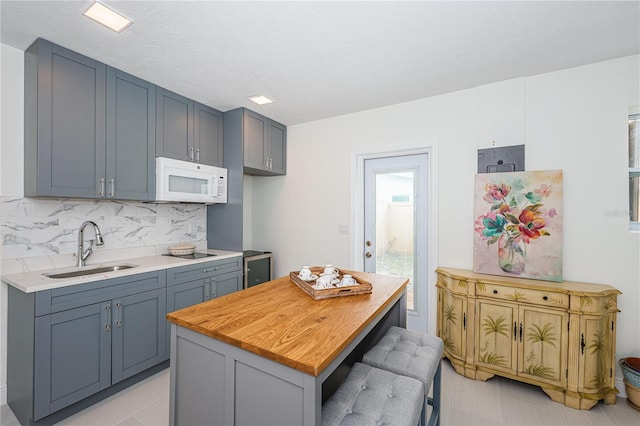 kitchen featuring tasteful backsplash, gray cabinets, a kitchen island, and sink