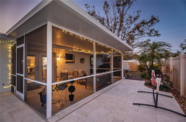 patio terrace at dusk featuring a sunroom