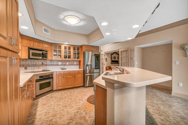 kitchen featuring light tile patterned flooring, sink, an island with sink, stainless steel appliances, and backsplash