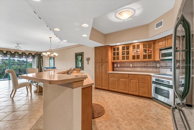 kitchen with sink, light tile patterned floors, appliances with stainless steel finishes, decorative backsplash, and decorative light fixtures