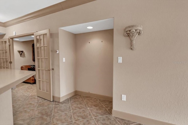 empty room featuring light tile patterned floors, ornamental molding, and french doors