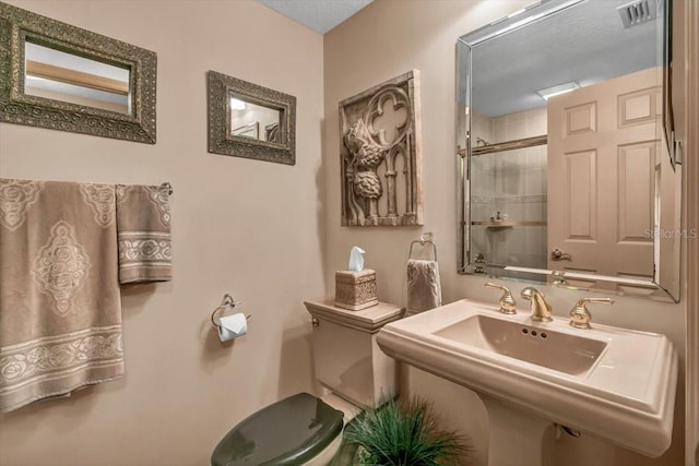 bathroom featuring toilet, sink, and a shower with shower door