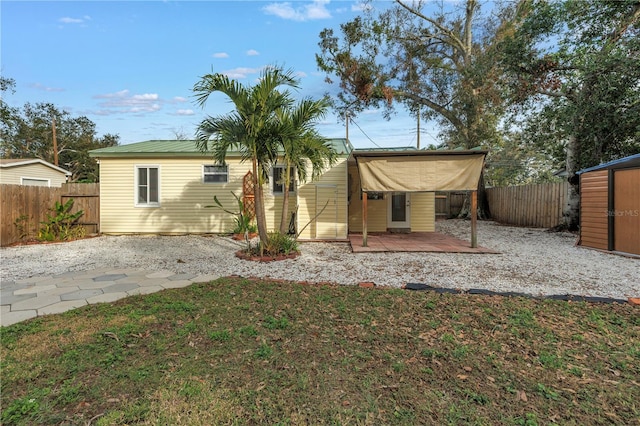 back of house featuring an outbuilding, a fenced backyard, a patio, and a storage unit