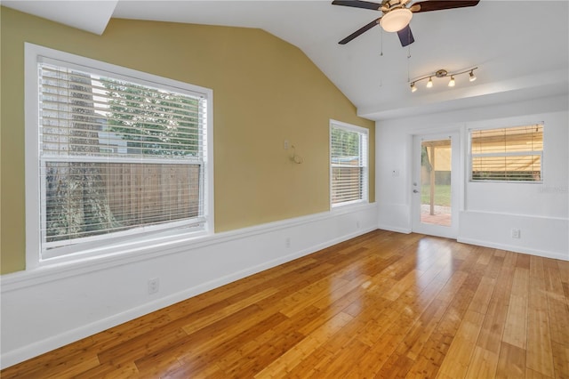 spare room featuring lofted ceiling, light wood-style floors, ceiling fan, and baseboards