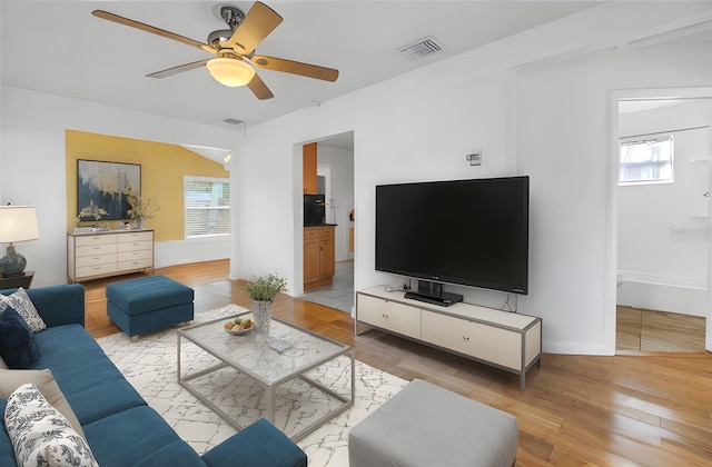 living area with baseboards, light wood finished floors, visible vents, and a ceiling fan