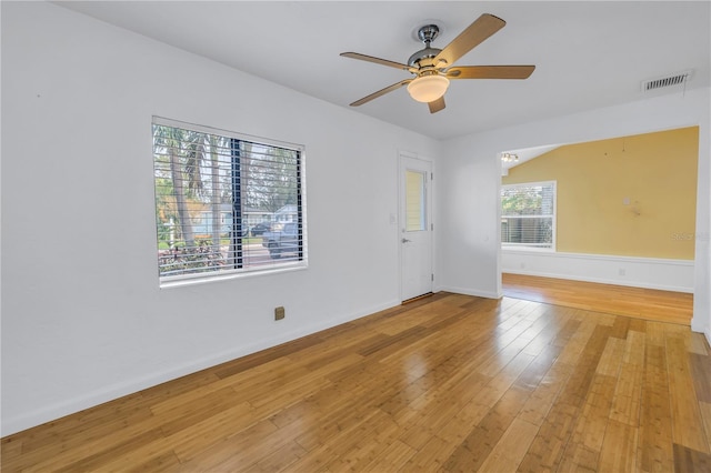 spare room featuring light wood-style flooring, a ceiling fan, visible vents, and baseboards