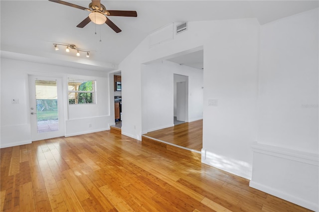 empty room featuring ceiling fan, wood finished floors, visible vents, baseboards, and vaulted ceiling