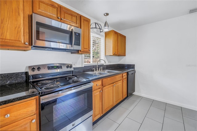 kitchen with light tile patterned floors, a sink, baseboards, appliances with stainless steel finishes, and brown cabinets