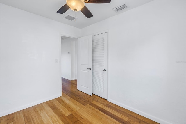 unfurnished bedroom featuring baseboards, a closet, visible vents, and wood finished floors