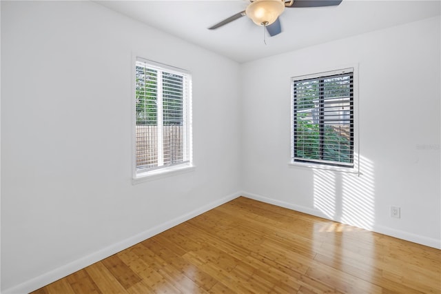 spare room featuring wood finished floors, a ceiling fan, and baseboards