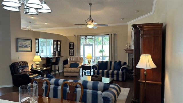 living room with a fireplace, a textured ceiling, ornamental molding, dark hardwood / wood-style flooring, and ceiling fan with notable chandelier