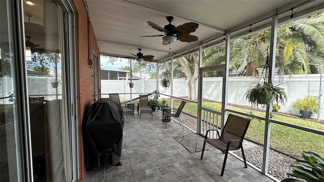 unfurnished sunroom featuring ceiling fan and plenty of natural light