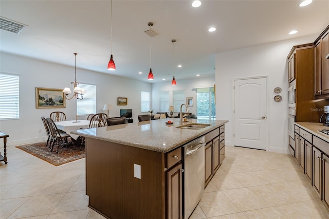 kitchen with sink, hanging light fixtures, stainless steel dishwasher, an island with sink, and light stone counters