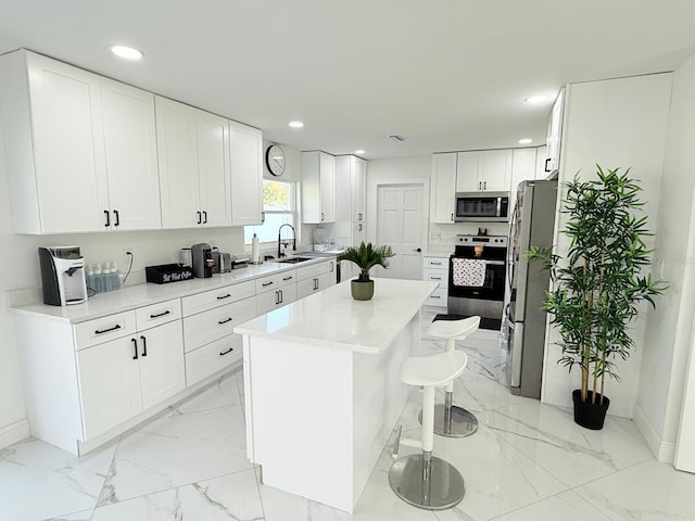 kitchen with white cabinetry, a center island, sink, stainless steel appliances, and a kitchen bar