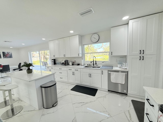 kitchen featuring white cabinetry, sink, dishwasher, a kitchen bar, and a kitchen island