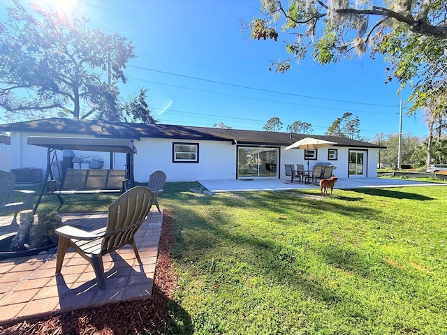 rear view of property featuring a lawn and a patio