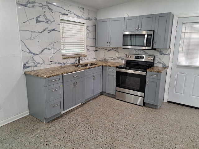 kitchen with appliances with stainless steel finishes, gray cabinetry, backsplash, and sink