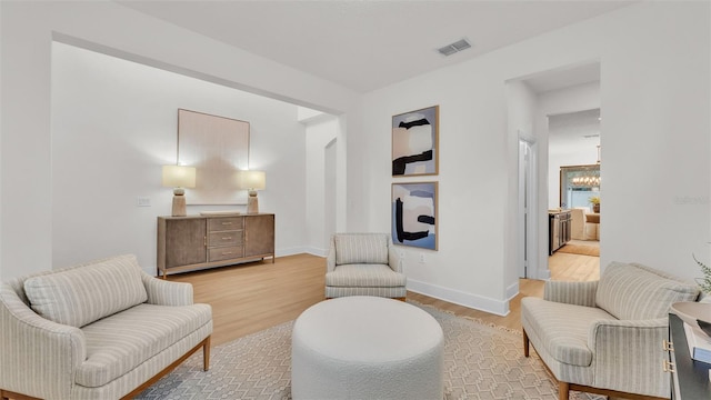 sitting room with a notable chandelier and hardwood / wood-style flooring