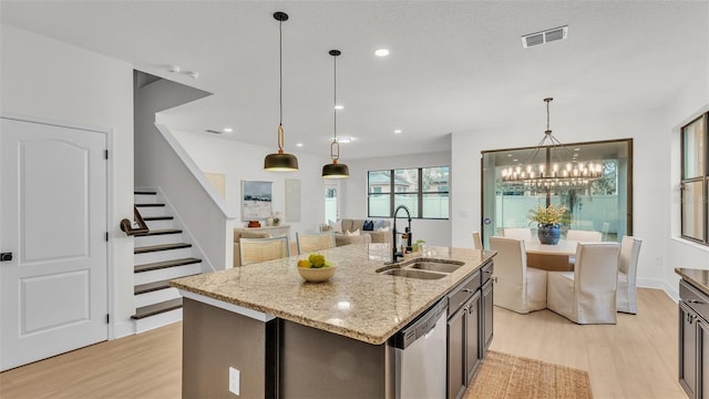 kitchen featuring a center island with sink, dishwasher, light hardwood / wood-style flooring, light stone counters, and sink