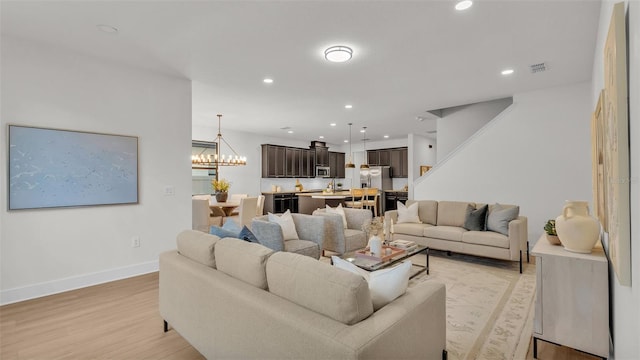 living room with light hardwood / wood-style flooring and a chandelier