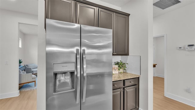 kitchen featuring light hardwood / wood-style floors, backsplash, stainless steel fridge, and dark brown cabinetry