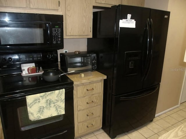 kitchen featuring light brown cabinetry, light tile patterned floors, and black appliances