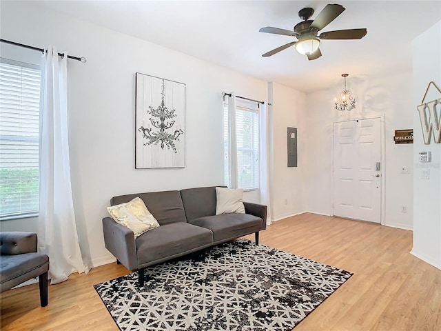 living room featuring hardwood / wood-style flooring, ceiling fan with notable chandelier, a healthy amount of sunlight, and electric panel