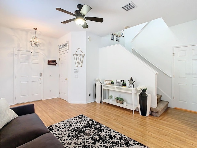 living room with ceiling fan with notable chandelier and wood-type flooring