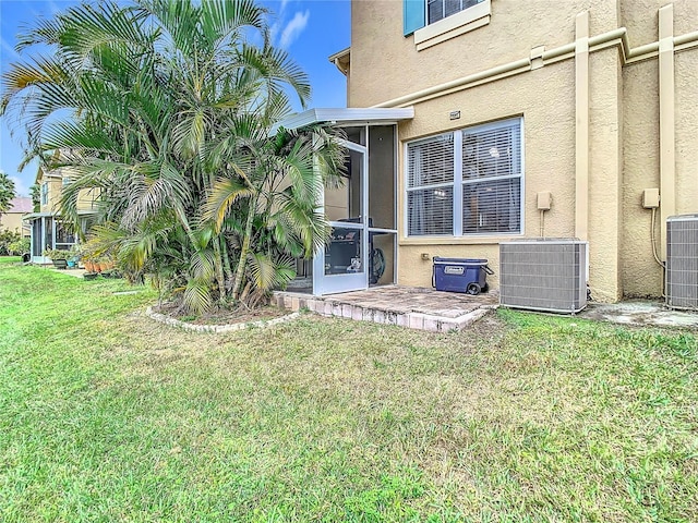 exterior space featuring a sunroom, a yard, and central AC