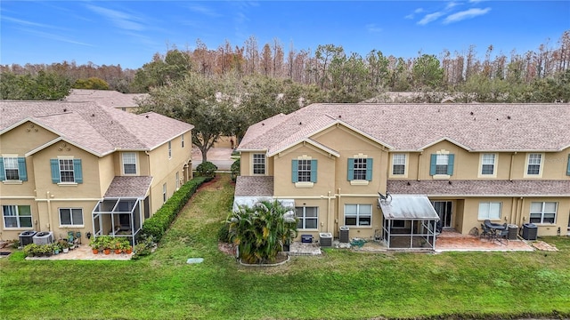 back of property with a lawn, a patio, and central AC