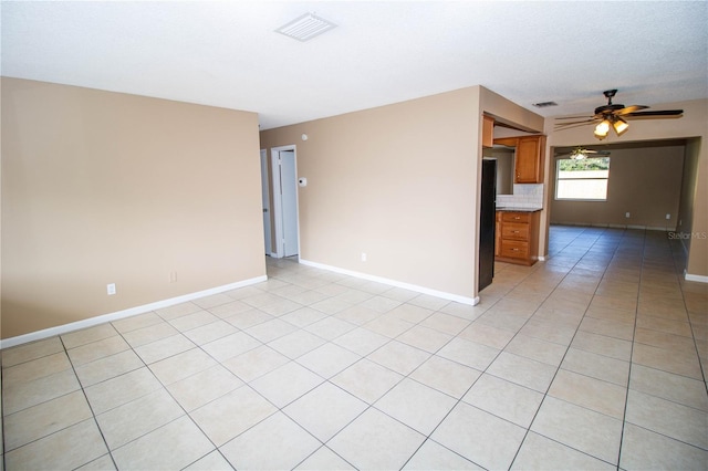 unfurnished room featuring a textured ceiling, ceiling fan, and light tile patterned flooring