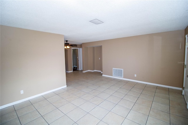 empty room featuring ceiling fan, light tile patterned flooring, and a textured ceiling