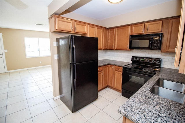 kitchen with dark stone counters, light tile patterned floors, and black appliances