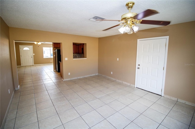 tiled empty room featuring ceiling fan and a textured ceiling