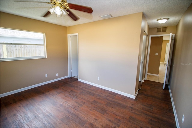 unfurnished room featuring dark hardwood / wood-style floors, ceiling fan, and a textured ceiling