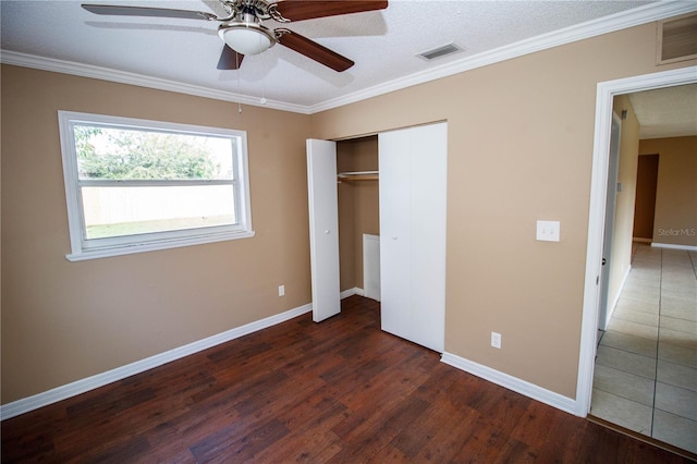 unfurnished bedroom featuring a closet, dark hardwood / wood-style floors, ceiling fan, and ornamental molding