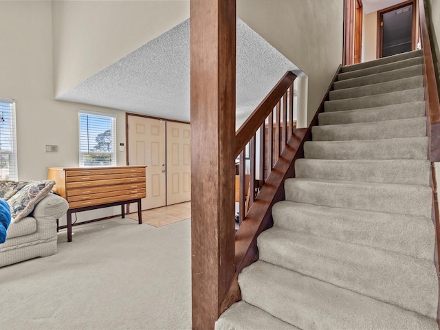 stairway with carpet and a textured ceiling