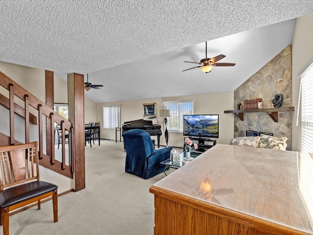 living room with a textured ceiling, light colored carpet, vaulted ceiling, ceiling fan, and a fireplace